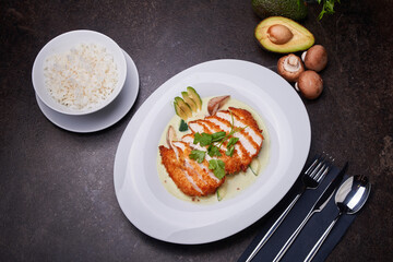 Chicken in coconut sauce and rice. Pan-asian dish top view on a dark table