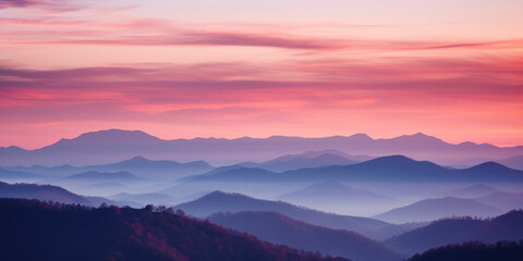 The mountains are shrouded in mist. A twilight shot of autumn mountains under a fading red orange purple sky.