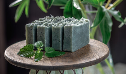 Pieces of refreshing natural handmade soap on a wooden stand with green leaves of fresh mint....
