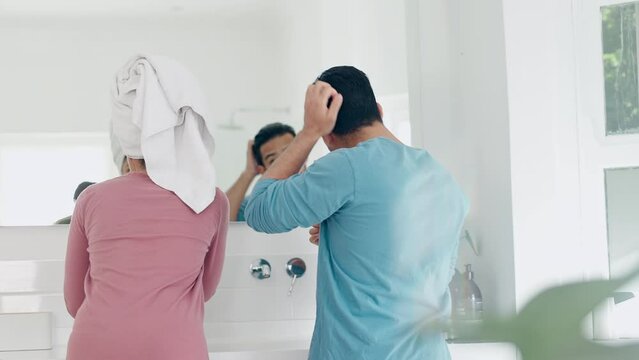 Back, hair and morning with a couple in the bathroom together for a grooming routine in their home. Mirror, health or beauty with a man and woman getting ready while grooming for skincare in a house