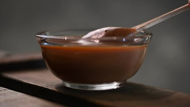 horizontal video of a glass bowls with dulce de leche with wooden spoon