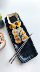 Overhead vertical view of gimbap roll served in a black long plate, a popular traditional authentic South Korean dish 