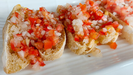 Close up of a vegan Bruschetta made from tomatoes and onions drizzled with olive oil, traditional Italian antipasto or starter