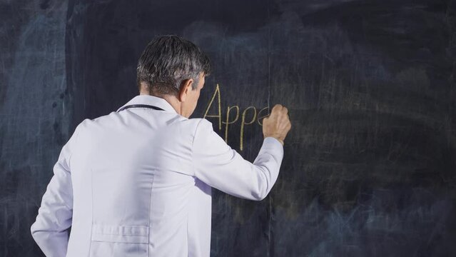 Male doctor writing appendicitis on the blackboard.