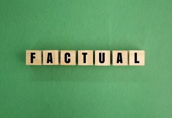 wooden cube with the word factual. the concept of fact. concerned with what is actually the case.