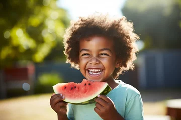Rolgordijnen Boy happily eating watermelon at a picnic.  © Jeff Whyte