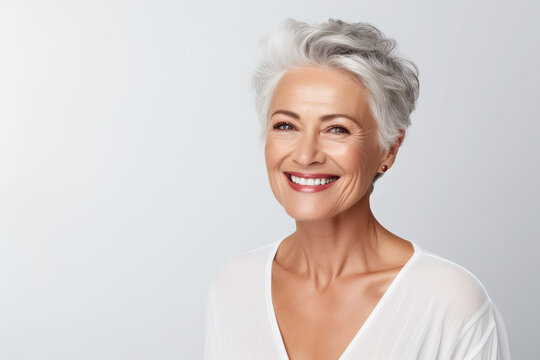 portrait of a beautiful senior woman and smiling with clean teeth and perfect skin isolated on light blue background, for spa advertising, copy space