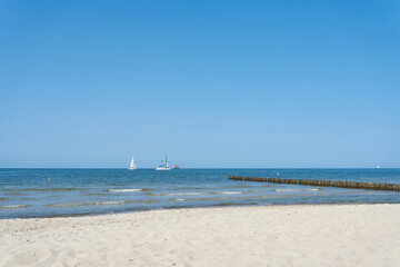 Strand bei Kühlungsborn an der deutschen Ostsee mit blauem Himmel und einigen Segelbooten am Horizont 
