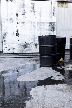 Oil Barrels In An Industrial Site Leaking Across The Pavement; Vancouver, British Columbia, Canada