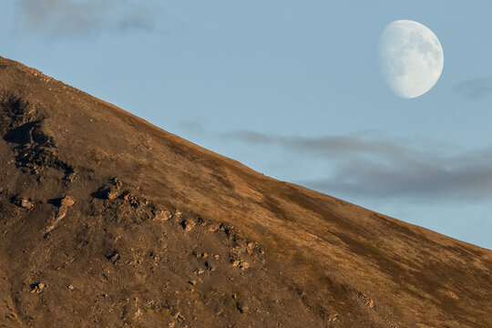 The Near Full Moon Over A Mountain In The Yukon Evening Skies; Yukon, Canada