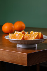 Sliced oranges on a porcelain plate, blurred background, wooden table, indoor shot, close-up