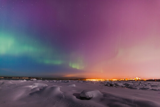 Northern lights shine above city skyline in this nighttime view from the tony knowles coastal trail in winter; Anchorage alaska united states of america