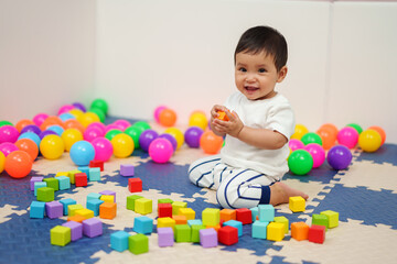 Fototapeta na wymiar happy infant baby playing wooden block toy in playpen