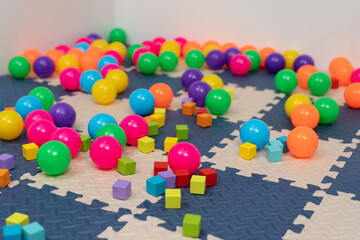 wooden block toy and colorful plastic balls on mat or jigsaw floor