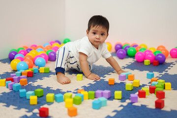 Fototapeta na wymiar infant baby playing wooden block toy in playpen