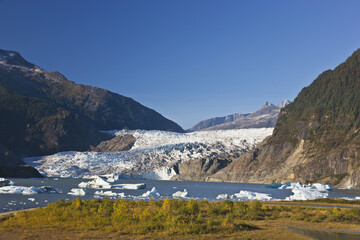 The Retreating Mendenhall Glacier Spilling Over The Mountains And Into Mendenhall Lake Under Blue Skies, Near Juneau; Alaska, United States Of America
