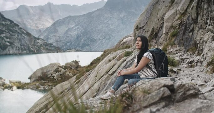 Young backpacker resting on a rock by a mountain lake in the Swiss alps