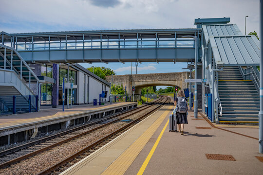Mature woman waits with luggage at a train station; United Kingdom