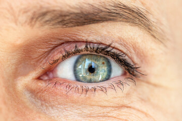 The green-blue eye of a middle-aged woman. Close-up. Front view.
