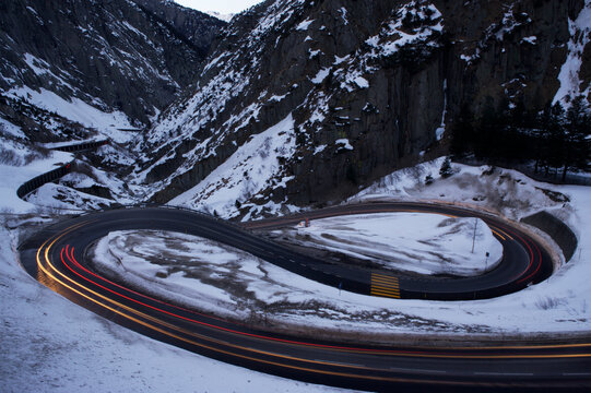 Car lights blur on a switchback road above San Gotthard tunnel in Switzerland; Andermatt, Switzerland