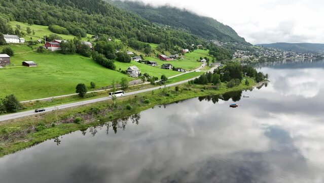 Aerial following white bus driving road E16 towards city of Voss with Vangsvatnet lake on the side - Voss Norway in background - Aerial