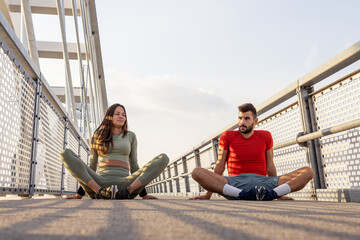 Young couple streching before jogging at the bridge