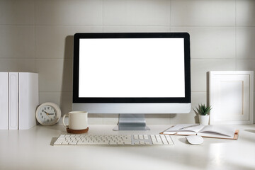 Minimal workspace with white screen computer and office supplies on white table.
