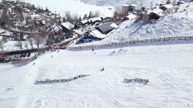 Aerial orbit of a person ascending the Farellones ski slope through the t-shaped drag lift, parallax effect of the snowy village of Farellones.