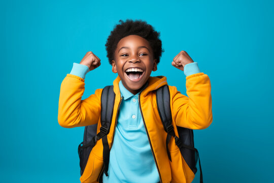 happy winner African American school boy on blue background celebrates new success, power, energy.