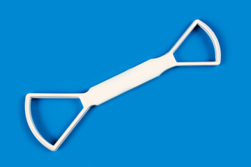 Tongue scraper on a blue background. Personal hygiene product. Plastic scraper for cleaning the tongue.