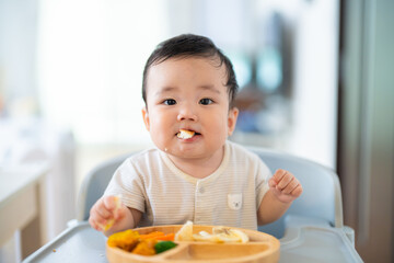 離乳食後期でをつかみ食べをしてご機嫌な生後9か月の赤ちゃん