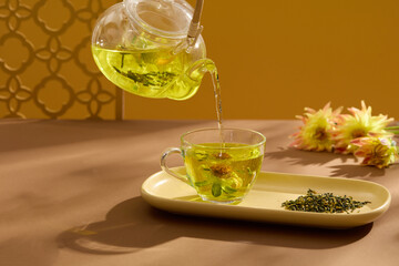 Mid- autumn festival concept with tea set of chamomilla tea decorated on brown background. Black space for mooncakes advertising. Front view