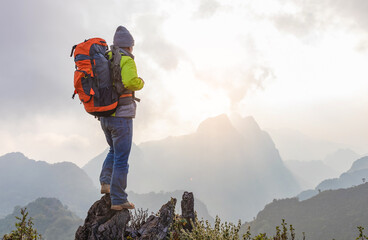 Obraz premium Hiker with backpack standing on top mountain sunset background. Hiker man hiking living healthy active lifestyle.