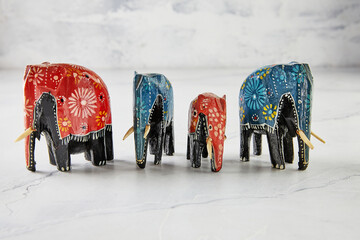 Elephant figurines of different colors and shapes on white marble