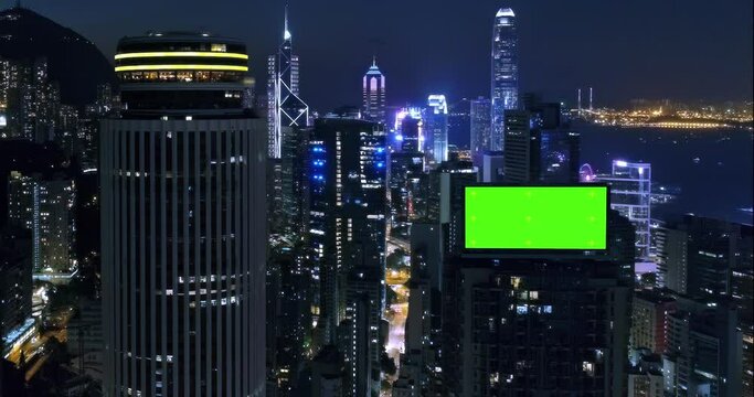 AERIAL. Top view of skyscrapers and green screen build board with tracking point. Bird view of modern city at night streets.