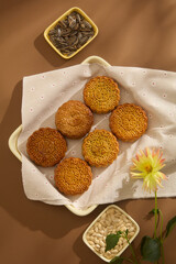 The rectangle tray containing delicious mooncakes decorated with trays of sunflower seed and pumpkin seed on brown background. Concept for Mid-Autumn Festival