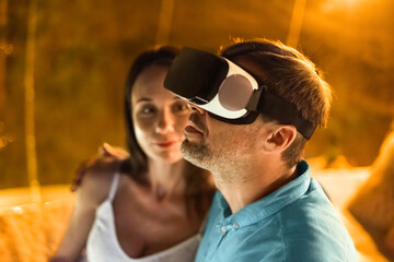 Man in VR glasses and wife inside tent at glamping