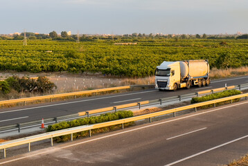 Isothermal Tank truck driving on highway. Oil and Gas Transportation and Logistics. Metal chrome...