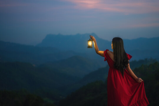 A woman standing with a lantern in the night on the mountain.