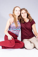 Couple of Two Winsome Caucasian Girlfriends Together While Sitting Embraced Over White Background.