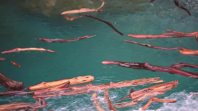 The flow of water carries the logs into the funnel. A stormy river washes away a forest, a flood.