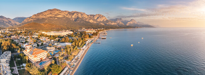 captivating charm of Kemer's landscape through stunning aerial photo, where hotels, a beautiful sea beach, and majestic mountains converge to create an idyllic panorama.