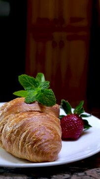 vertical video croissant with mint and strawberries on a white plate place for texts background advertising postcard banner blank for any social networks of the Internet invitation to dinner breakfast