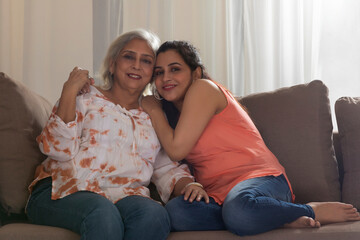 Obraz premium A SENIOR ADULT MOTHER AND YOUNG DAUGHTER SITTING AND POSING IN FRONT OF CAMERA