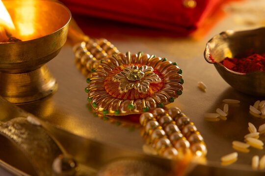 Close up of a beautiful rakhi kept in a plate with diya and rice