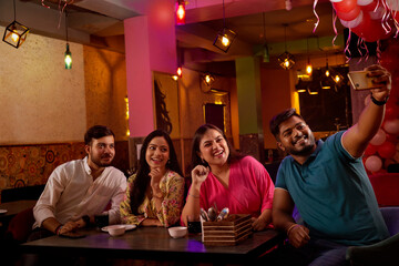 Friends taking selfie on mobile phone at restaurant