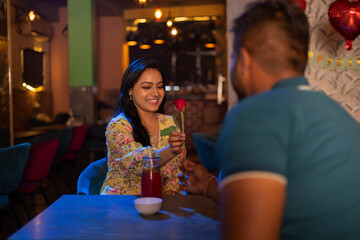 Man giving red rose to his girlfriend at a restaurant