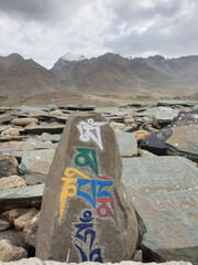 Inscribed stones with Buddhist mantra Om Mani Padme Hum with the background of mountains of Padum, Zanskar Valley, Ladakh, INDIA 