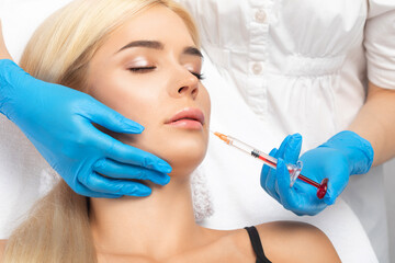 Cosmetologist does injections for lips augmentation and anti wrinkle in the nasolabial folds of a...