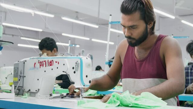 Skilled Indian men or male workers, artisans, or tailors busy working on the sewing machine in a busy textile workshop or the garment industry or factory, Jaipur, India